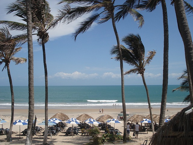 "Praia de Jericoacoara no Ceará, Brasil, com suas águas cristalinas, dunas de areia e a famosa Pedra Furada ao fundo."