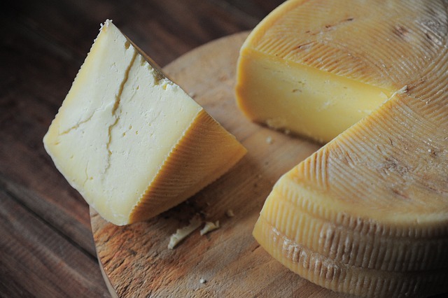 Queijo Minas Artesanal em uma tábua de madeira, com fatias cortadas, acompanhado de café e utensílios rústicos típicos de Minas Gerais.