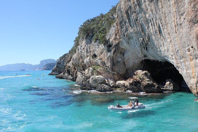 "Vista de uma praia paradisíaca na Sardenha, Itália, com águas cristalinas azul-turquesa, areias brancas e vegetação mediterrânea ao fundo."