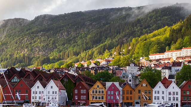 "Vista panorâmica do fiorde Geirangerfjord, na Noruega, cercado por montanhas verdes e águas cristalinas, sob um céu azul claro."